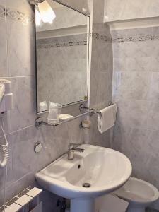 bagno bianco con lavandino e specchio di Hotel Umbria a Perugia