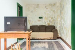 a living room with a couch and a television at Central Flat 2 quartos - Centro de Búzios in Búzios