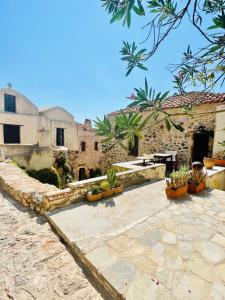 a stone courtyard with potted plants and a building at vecchia casa in Monemvasia