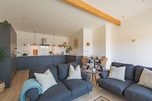 a living room with two blue couches and a kitchen at The Parlour by Bloom Stays in Stalisfield