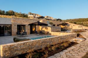 een stenen huis met een zwembad en een stenen muur bij Fari Stone Villas in Skala Marion