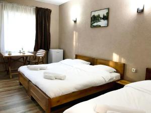 a hotel room with two beds and a table at Lesnovo House Tomevski in Lesnovo