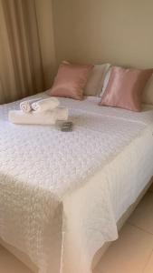 a white bed with white sheets and pink pillows at FlatsRose CH Flamboyant Conforto e qualidade in Goiânia
