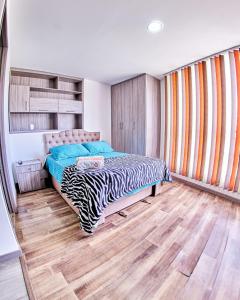 1 dormitorio con 1 cama y suelo de madera en MINISUITES Centro Pasto, en Pasto