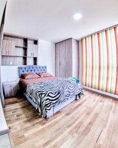 1 dormitorio con cama con estampado de cebra y suelo de madera en MINISUITES Centro Pasto en Pasto