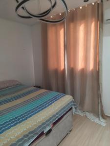 a bedroom with a bed and a window with a chandelier at Condomínio reserva da cidade in Manaus