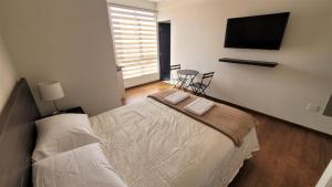 a bedroom with a bed and a flat screen tv at LYRA in Cochabamba