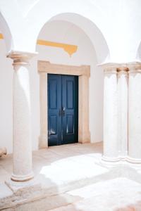 Una puerta azul en una habitación blanca con columnas en O Conventinho, en Évora