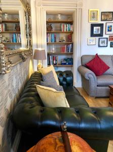 a living room with a leather couch and a chair at Heart of Ayr: elegant townhouse in central Ayr in Ayr