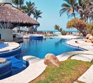 a swimming pool at a resort with palm trees and the ocean at Nuevo 3R 3B 1E Club Playa Gratis Tenis Padel Diamante Albercas in Acapulco