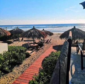 a beach with umbrellas and chairs and the ocean at Nuevo 3R 3B 1E Club Playa Gratis Tenis Padel Diamante Albercas in Acapulco