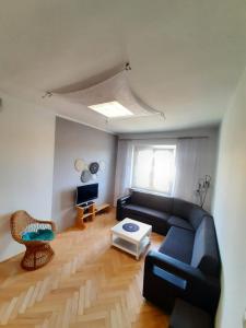 salon z czarną kanapą i oknem w obiekcie Apartament Kaszownik w Toruniu