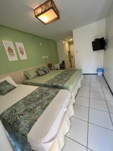 una camera d'albergo con due letti e una televisione di Gran Lençois Flat Residence - Barrerinhas (Aptº Particular) a Barreirinhas