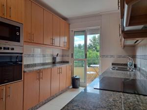 una cocina con armarios de madera y una gran ventana en Apartamento con vistas, amplio y luminoso, en Monforte de Lemos 4 fotos más