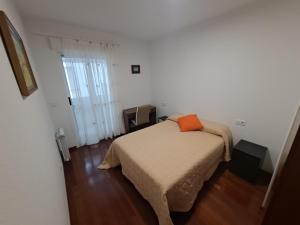 a bedroom with a bed with an orange pillow on it at Apartamento con vistas, amplio y luminoso in Monforte de Lemos