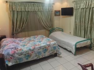 een slaapkamer met 2 bedden en een televisie en gordijnen bij Alexander b&b in Alajuela +13 foto's