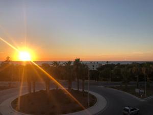 um pôr-do-sol sobre uma estrada com palmeiras e o oceano em Casa Mare di Ponente em Érice