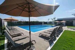 a pool with chairs and an umbrella next to a pool at Hacienda en Primavera, descanso Familiar total in Puerto Vallarta