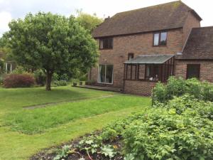 una casa de ladrillo con un árbol en el patio en Bramley Cottage Holidays en Chichester