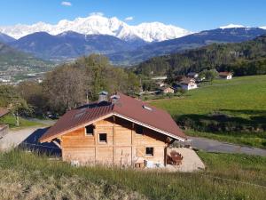 a wooden barn with snow covered mountains in the background at L'Eterlou 74 in Sallanches