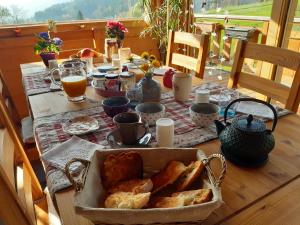 uma mesa com pão e chávenas de café e sumo de laranja em L'Eterlou 74 em Sallanches