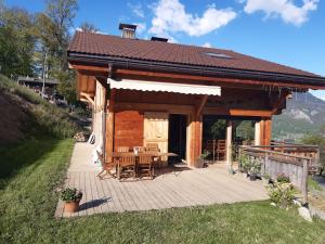 a log cabin with a table and chairs on a deck at L'Eterlou 74 in Sallanches