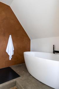 B&B Leonie في Alveringem: حوض استحمام أبيض في حمام مع درج