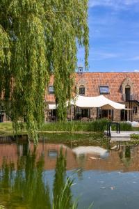 un edificio con una tienda junto a un estanque en B&B Leonie, en Alveringem