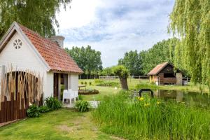 ein kleines weißes Haus mit einem Garten und einem Teich in der Unterkunft B&B Leonie in Alveringem