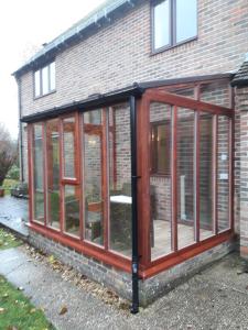 a screened in greenhouse on the side of a house at Bramley Cottage Holidays in Chichester