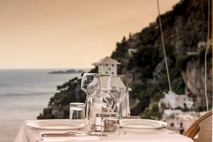 a table with plates and wine glasses on top of it at Hotel Villa Gabrisa in Positano