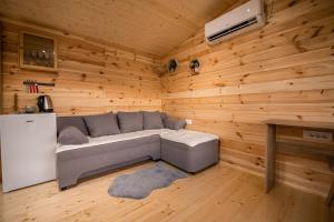 ein Wohnzimmer mit einem grauen Sofa in einem Holzzimmer in der Unterkunft Sunny in Nikšić
