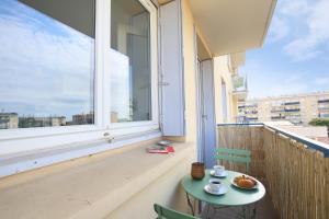 una mesa y sillas en un balcón con una gran ventana en expat renting - Le Bohème Nature - Proche Airbus, en Colomiers