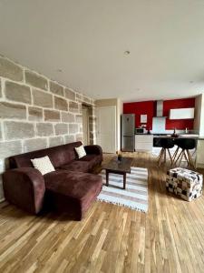 ein Wohnzimmer mit einem braunen Sofa und einer Ziegelwand in der Unterkunft Casa Zola - Magnifique T3 Climatisé - Centre Ville in Brive-la-Gaillarde