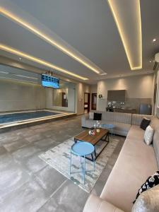 sala de estar con sofá, mesa y piscina en شاليهات ضوء, en Taif