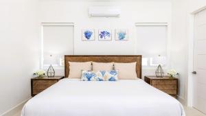 a white bedroom with a large bed with two night stands at New Luxury 8 Bedroom Sunset Bay Villa in Long Bay Hills