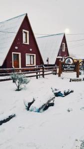 a barn covered in snow next to a fence at Cabañas del Rosario in Puerto Santa Cruz