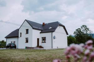 a white house with a black roof at Dom Wypoczynkowy - Alexander in Cisiec