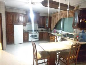 a kitchen with wooden cabinets and a table with chairs at City Center Furnished Apartment in Madaba