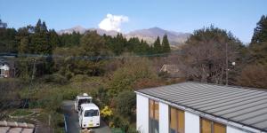 un furgone bianco parcheggiato di fronte a una casa con le montagne. di Minami Aso Guest House Hana hana - Vacation STAY 13316 a Takamori