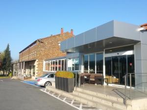 a building with a car parked in a parking lot at Ruta Jacobea in Lavacolla