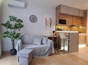 a living room with a couch and a clock on the wall at Malta Delux Apartment, free parking, self check-in 24h, air-conditioning in Poznań