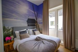 a bedroom with a large bed with a painting on the wall at 2L De Volharding in Leiden