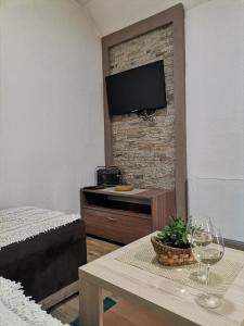 a living room with a table and a tv on a brick wall at Vikendica Čeperković #2 in Kopaonik