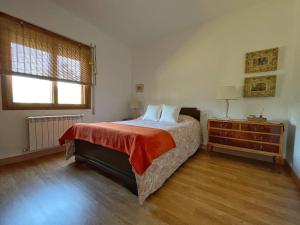 a bedroom with a bed and a dresser and a window at ENTRETOXOS in Ribadavia