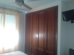 1 dormitorio con armario de madera y TV en Hostal Restaurante el Cazador, en Nuévalos