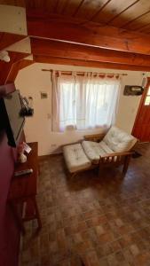 sala de estar con sofá blanco y ventana en Cabañas del Rosario en Puerto Santa Cruz