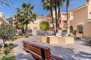 un banco de parque frente a un edificio con palmeras en Cielo Sur Vera Playa, en Vera