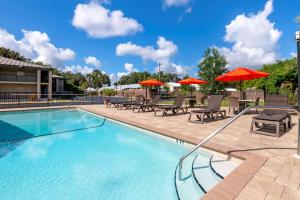 a swimming pool with patio furniture and umbrellas at Best Western Inn Of Palatka in East Palatka