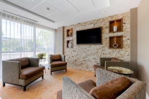 a living room with a tv on a brick wall at Best Western Plus North Miami-Bal Harbour in North Miami